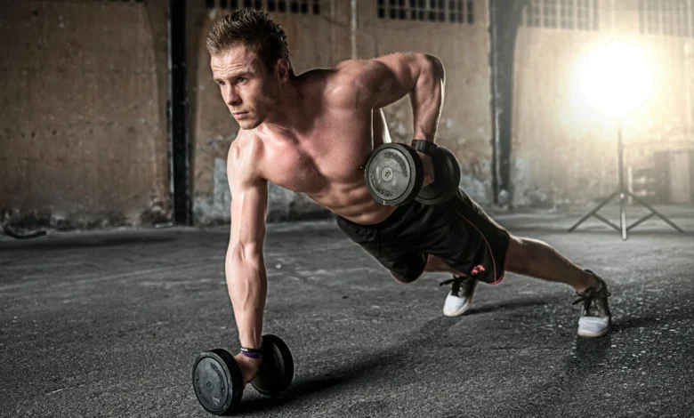 Balanced Training Schedule: A fit man performs a complex dumbbell exercise in plank position, exemplifying strength, balance, and dedication to a comprehensive fitness routine in a gritty, urban setting.